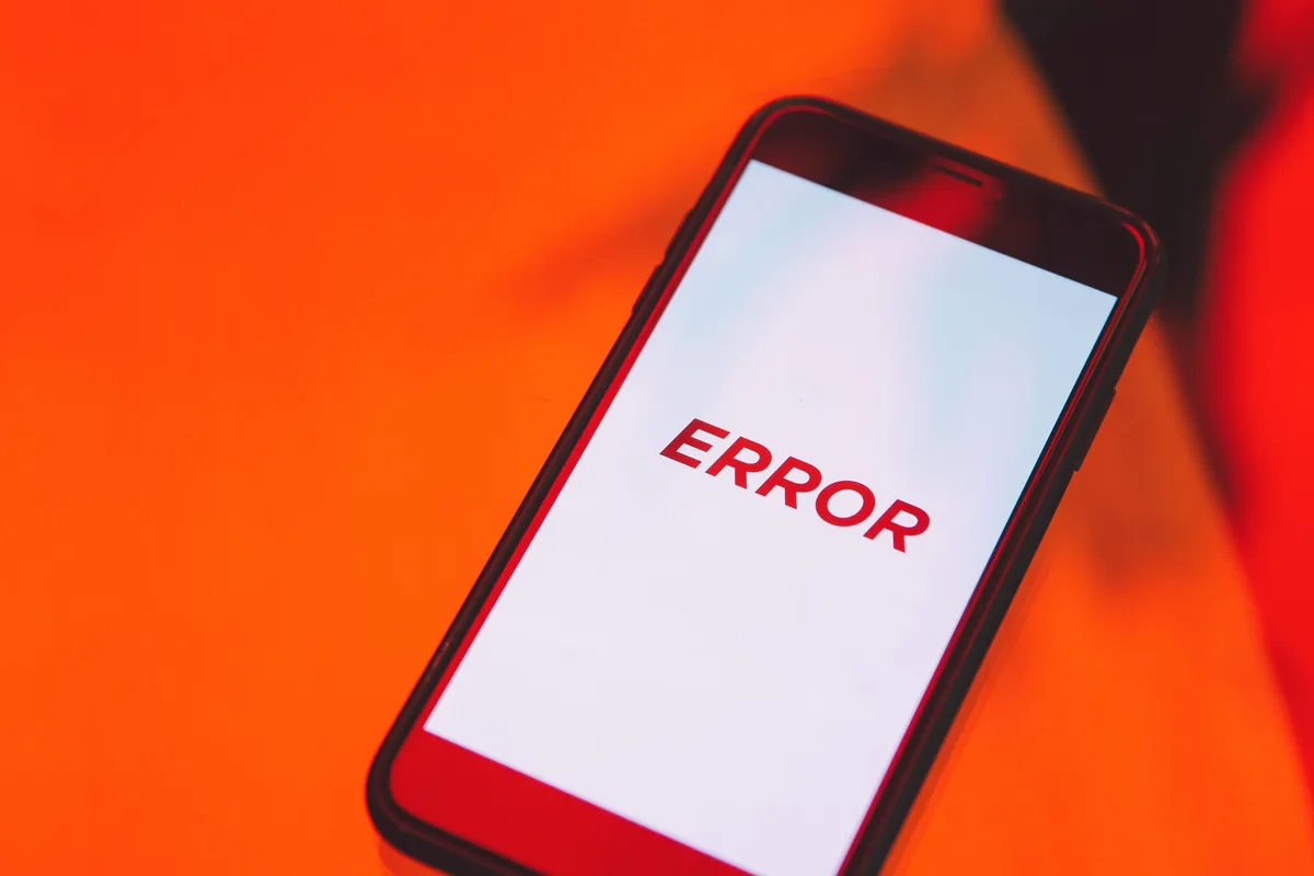 Smartphone auf orangefarbenem Untergrund, auf dem Display steht das Wort Error